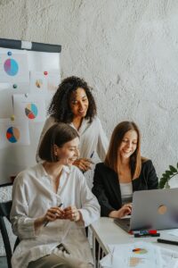 Trois femmes d'affaires collaborent avec des graphiques et un ordinateur portable dans un environnement de bureau moderne.