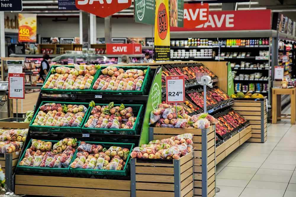 Étagères de produits frais dans un supermarché avec paniers et prix visibles