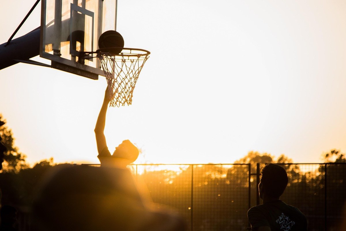 Joueur de basket-ball marquant un panier au coucher du soleil