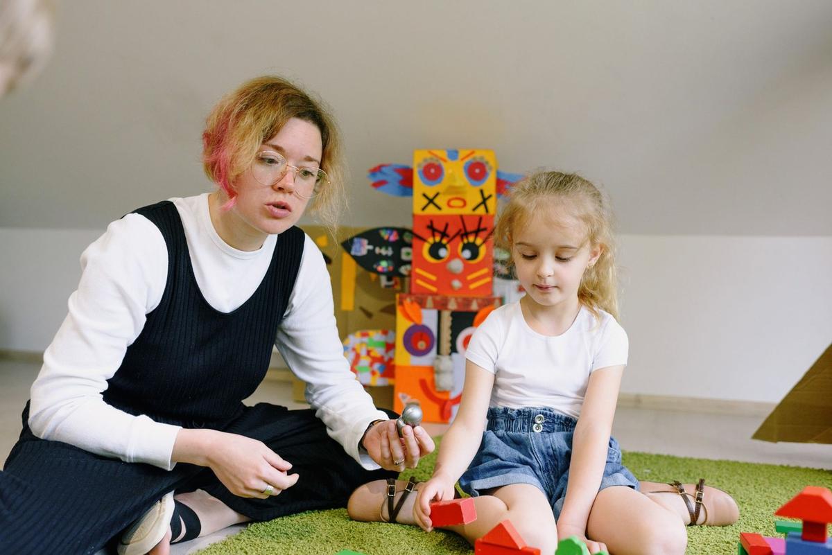 Femme et enfant assis sur un tapis, manipulant des blocs de construction