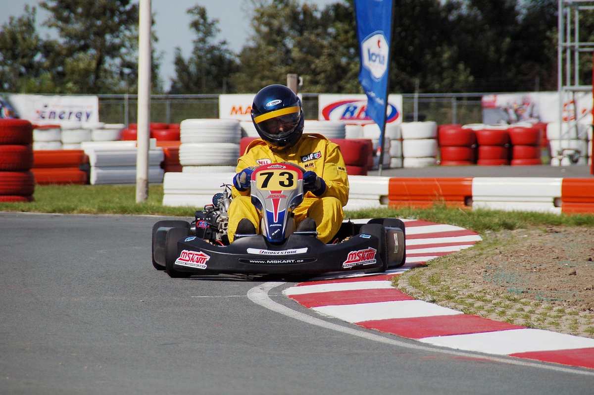 Un coureur en kart jaune 73 tourne sur virage de circuit Un coureur en kart jaune 73 tourne sur virage de circuit