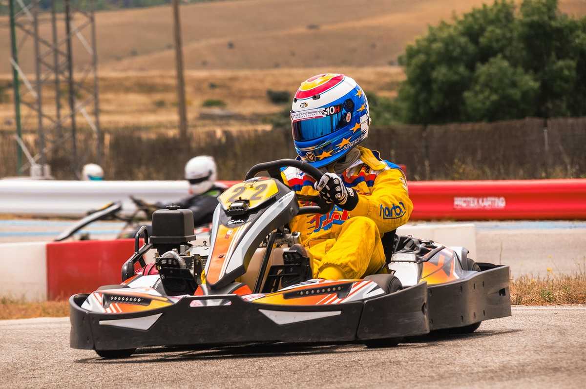 Pilote de karting en tenue jaune et casque coloré sur piste Pilote de karting en tenue jaune et casque coloré sur piste